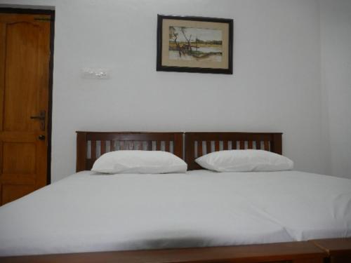 a white bed with two pillows in a bedroom at Temple Courtyard in Chengannūr