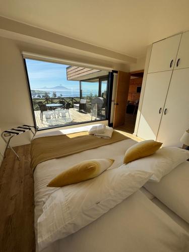 a large bed in a room with a large window at Cabañas Vista Volcanes del Sur in Llanquihue