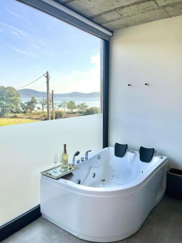a white tub in a room with a large window at Hotel VIDA Devalar Do Mar in Camariñas