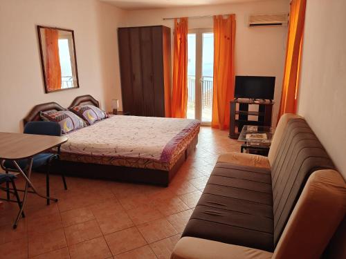 a bedroom with a bed and a couch and a television at Villa Palma in Prijevor