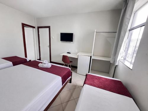 a room with two beds and a desk and a computer at Hotel Pousada Central in Feira de Santana
