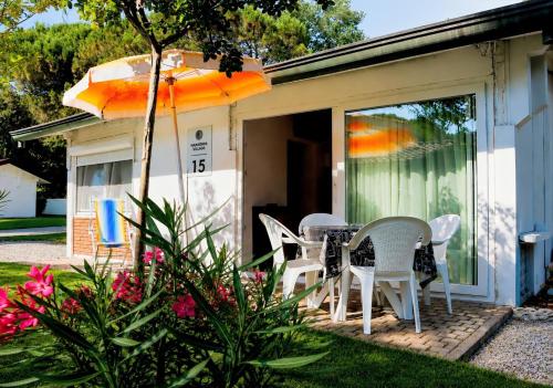 a patio with a table and chairs and an umbrella at Harmonia Village in Lido di Jesolo