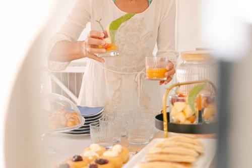 Eine Frau hält ein Glas Orangensaft neben einem Tisch mit Essen. in der Unterkunft Praja vecchia in Praia a Mare