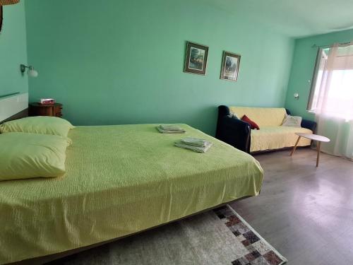 a bedroom with a green bed and a couch at Apartman Dejanović 2 in Veliko Gradište