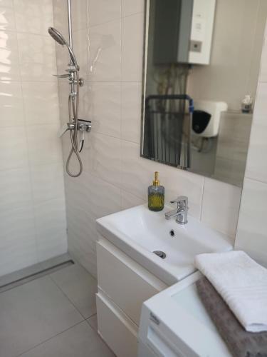 a white bathroom with a sink and a shower at Apartament Biała Przystań in Nowy Sącz