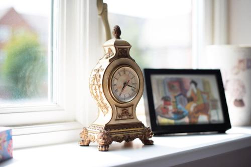 a clock sitting on a table next to a picture at 4 Bedroom Town House with Parking in Shrewsbury