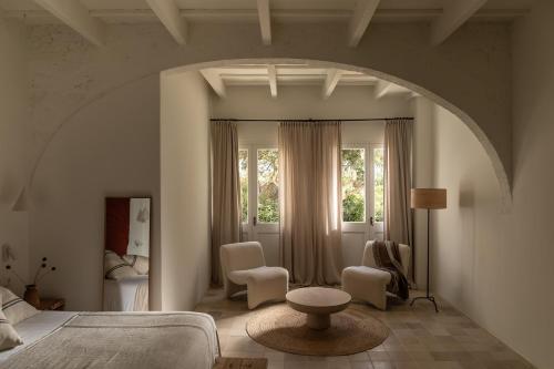 a bedroom with a bed and chairs and a window at Hotel Sant Ignasi in Ciutadella