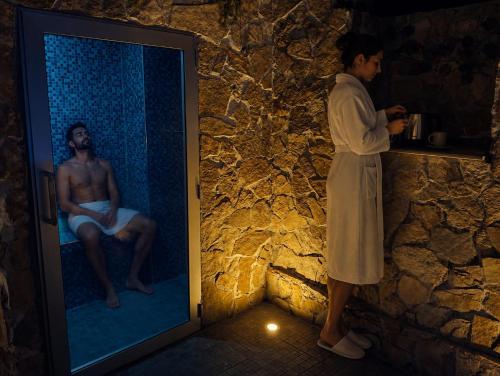 a woman standing in a bathroom looking at a man in a mirror at SPA SUITE SICILIA - Suite con Spa privata ad uso esclusivo Jacuzzi Sauna Hammam in Rosolini