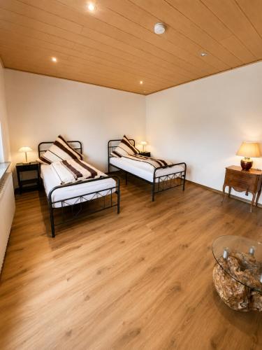 two beds in a room with wooden floors at Ferienwohnung Maison Maurus nahe Idar-Oberstein in Mörschied