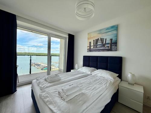 a bedroom with a large bed with a large window at Apartment & Room MARINA BORKI - Apartamenty RÓŻA WIATRÓW in Augustów