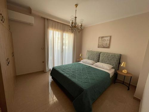 a bedroom with a green bed and a chandelier at Villa Dino in Kalithies