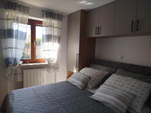 a bedroom with a bed with pillows and a window at Apartment Elio 1606 in Labin