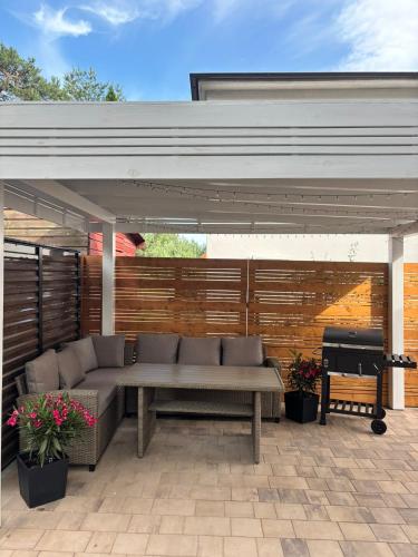 a patio with a couch and a bench under a pavilion at Trzy Tarasy Swornegacie in Swornegacie