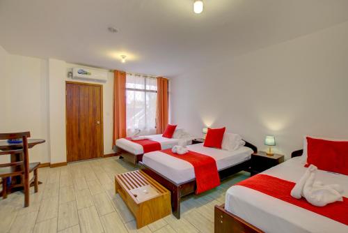 a room with two beds with red and white sheets at Hotel Red Booby in Puerto Ayora