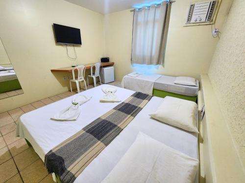 a hotel room with two beds and a television at Guarany Hotel Express in João Pessoa
