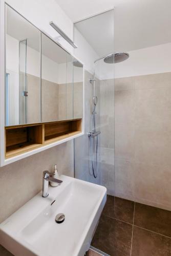 a bathroom with a white sink and a shower at Beach SUN and FUN Penthouse in Podersdorf am See