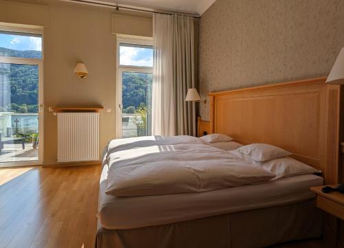 una camera da letto con un grande letto e una grande finestra di Hotel Schön am Rhein a Rüdesheim am Rhein