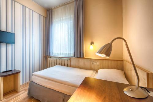a hotel room with a bed and a desk and a lamp at enjoy hotel Berlin City Messe in Berlin