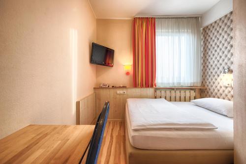 a small room with a bed and a television at enjoy hotel Berlin City Messe in Berlin