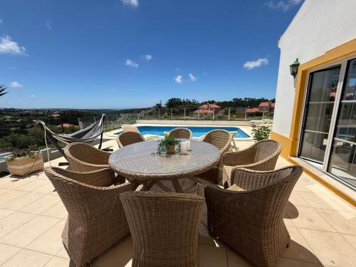a table and chairs on a patio with a pool at Villa Ericeira in Ericeira