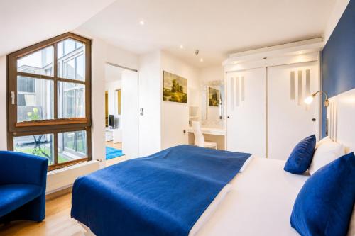 ein Schlafzimmer mit einem blauen Bett und einem Fenster in der Unterkunft Hotel Rivoli Charme in München
