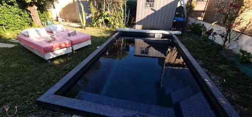 a pool of water with a pink bed and a couch at La Casita in Avignon