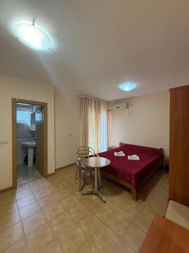 a room with a red bed and a table and a bathroom at Vila Laguna in Sutomore