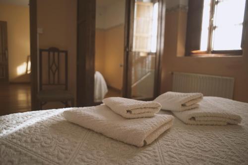 a bed with white towels on top of it at Casa Pousadoira in Miño