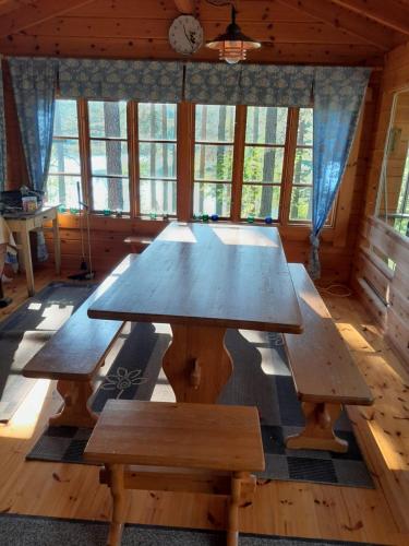 ein großer Holztisch in einem Raum mit Bänken in der Unterkunft Forest lodge in Lohja