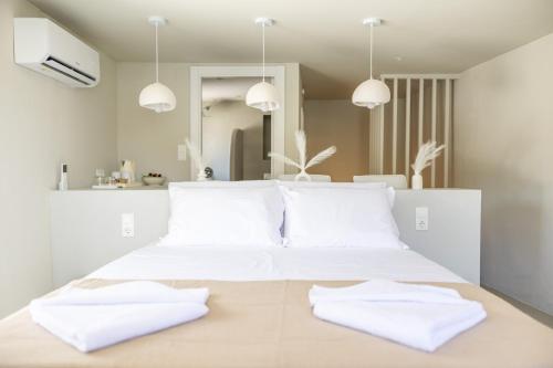 a bedroom with a white bed with white pillows at Nama Suites in Skopelos Town
