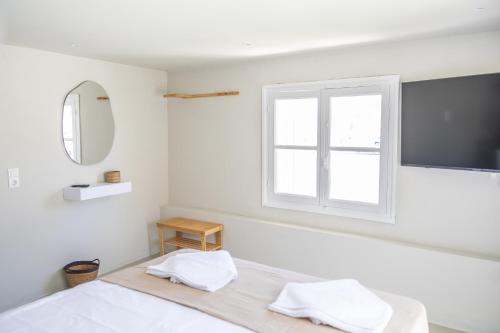 a white bedroom with a bed and a window at Nama Suites in Skopelos Town
