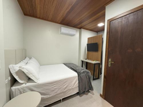 a small bedroom with a bed and a wooden door at Rio Jordao Hotel in Siderópolis