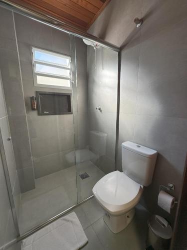 a bathroom with a toilet and a glass shower at Rio Jordao Hotel in Siderópolis
