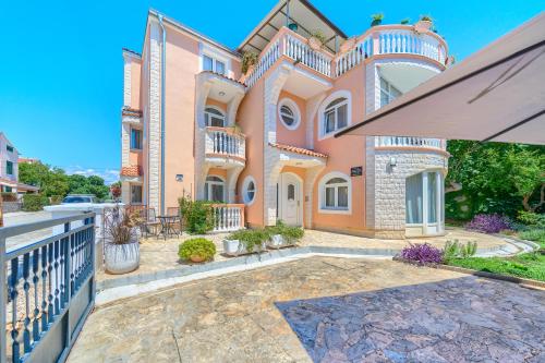 a large pink house with a balcony at Garden House Vodice in Vodice