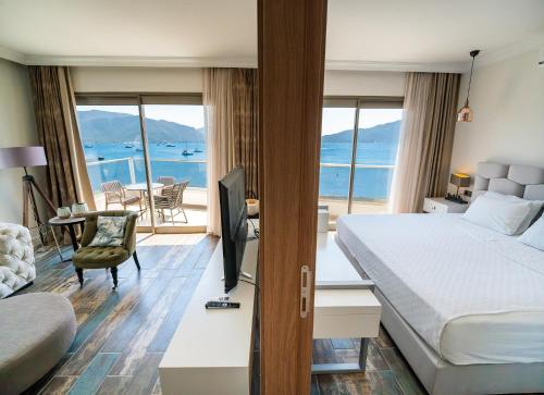 a hotel room with a bedroom with a bed and a television at Aurasia Beach Hotel in Marmaris