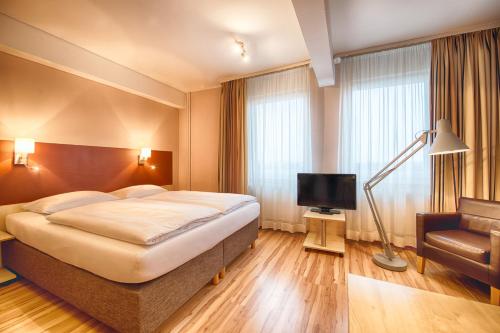 a hotel room with a bed and a chair and a television at enjoy hotel Berlin City Messe in Berlin