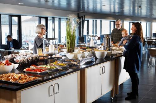 Un groupe de personnes autour d'un buffet de nourriture dans l'établissement Cabinn Aalborg, à Aalborg