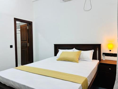 a bedroom with a bed with white sheets and yellow pillows at Luna Mara in Arugam Bay