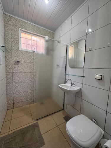 a bathroom with a toilet and a shower and a sink at Chalés Talismã in Caconde