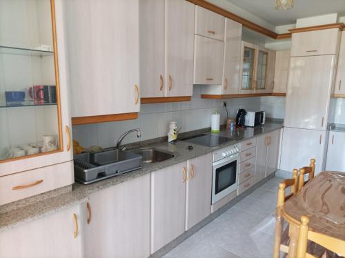 a kitchen with white cabinets and a sink at Refugio Mar de Boiro in Boiro