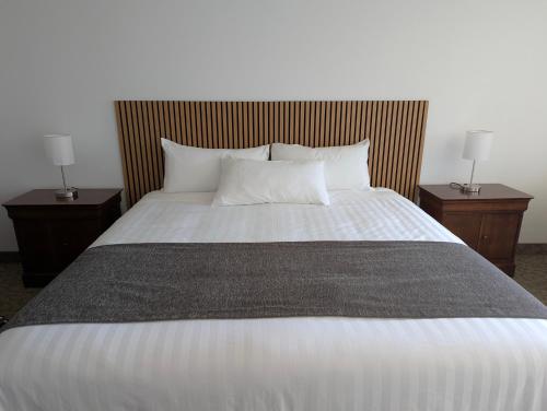 a large bed with two nightstands and two lamps at Auberge des 21 in La Baie