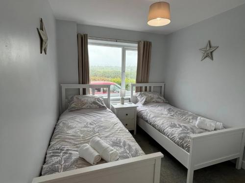 two beds in a room with a window at Llwyn Eithin in Benllech