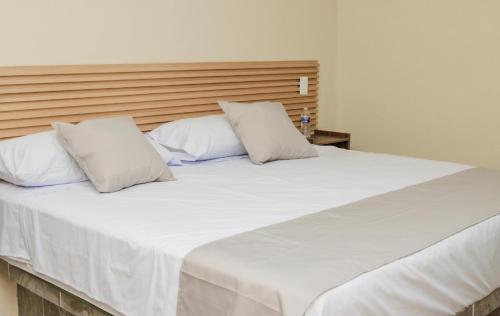 ein großes weißes Bett mit zwei Kissen darauf in der Unterkunft Hotel & Suites JM in Orizatlán