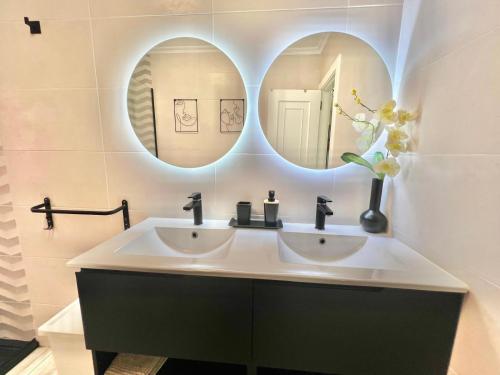 a bathroom with two sinks and two mirrors at Casa baja a la playa in Bueu