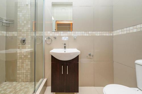 a bathroom with a sink and a glass shower at Diamond Style Guesthouse in Gqeberha