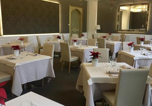a restaurant with white tables and chairs with red flowers on them at Blue Dream Hotel in Monselice