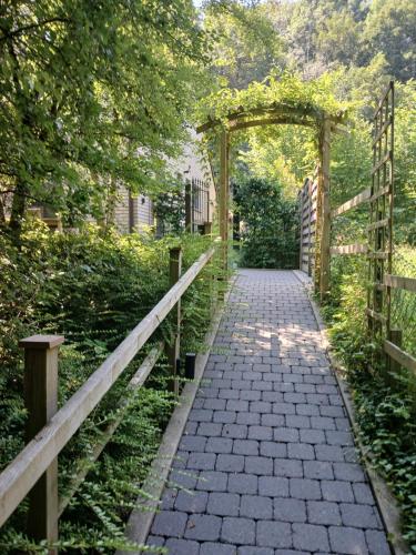 a stone pathway with an arch and a fence at Le Loft du Renard, gîte cosy au coeur de la nature boisée à Namur Wépion, une parenthèse douce dans la vallée mosane in Namur