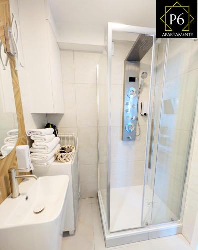 a white bathroom with a shower and a sink at P6 Lipowa in Pisz