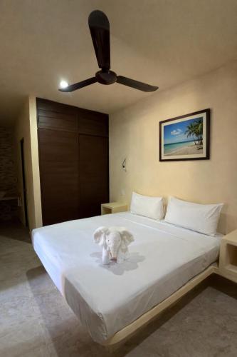 a white dog sitting on a bed with a ceiling fan at Jardín del Mar by ÓOL Hotels in Holbox Island