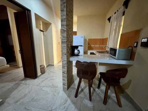 a kitchen with a counter and two chairs in a room at Jardín del Mar by ÓOL Hotels in Holbox Island